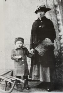 Auf dem schwarz/weiß Foto ist Fanny Metzger mit ihren Sohn Chaim und einem Holzschlitten zu sehen.