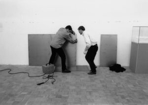 Im Ausstellungsraum sind zwei Männer mit dem Verschweißen der Arbeit beschäftigt.