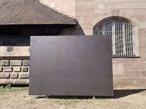 The photo shows the finished installation, a 3.60 x 2.60 m brown-gray steel plate, in front of the Kunsthalle Nürnberg.