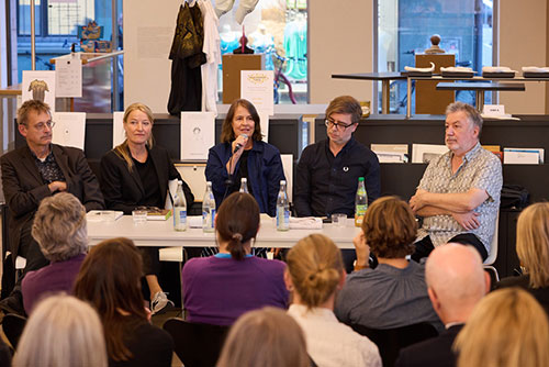 The discussion with Michaela Melián at the microphone and four other people at a table in front of the audience in the foyer of the Kunsthalle Nürnberg.